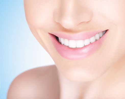 This is an alt text of a closeup of a woman smiling with bright white teeth.